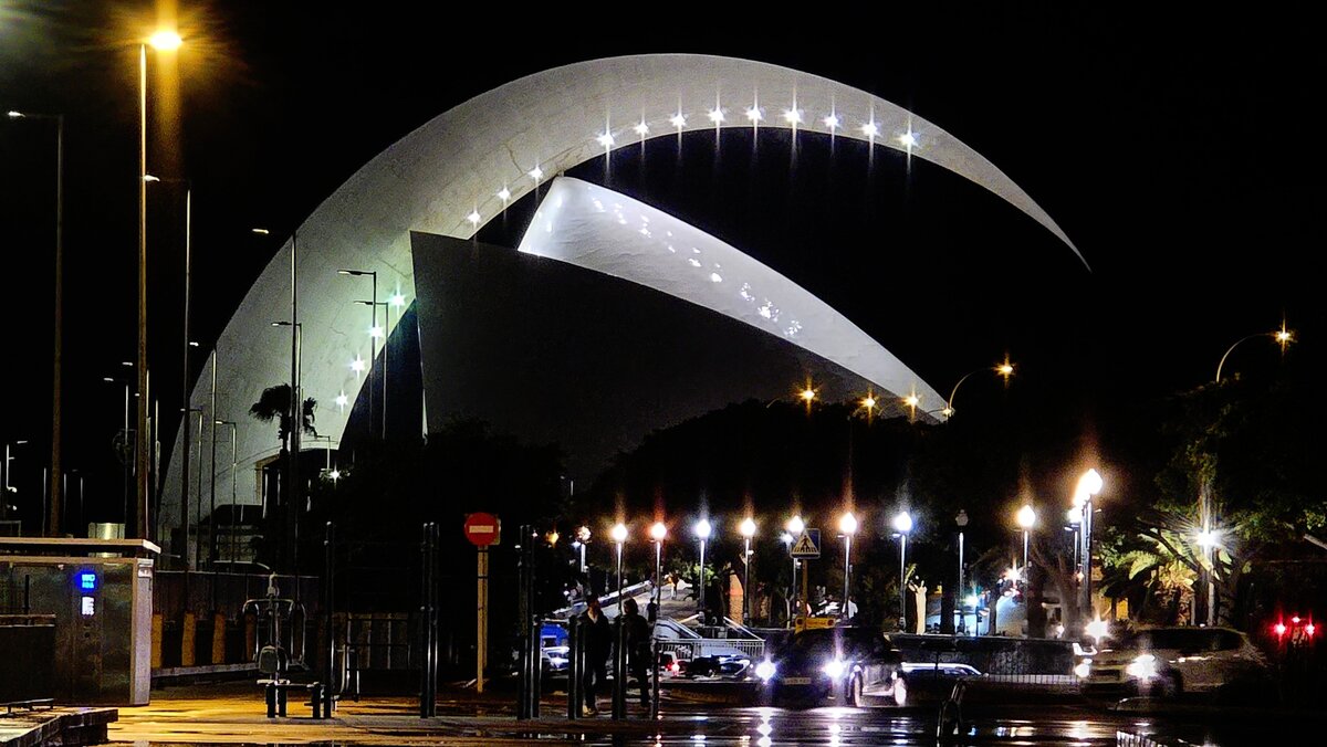 Oświetlone Auditorio de Tenerife w Santa Cruz nocą, po deszczu.