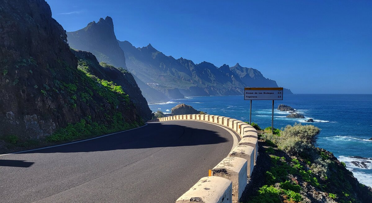 Droga w górach Anaga na Teneryfie, drogowskazy do Roque de las Bodegas i Taganana oraz ocean.