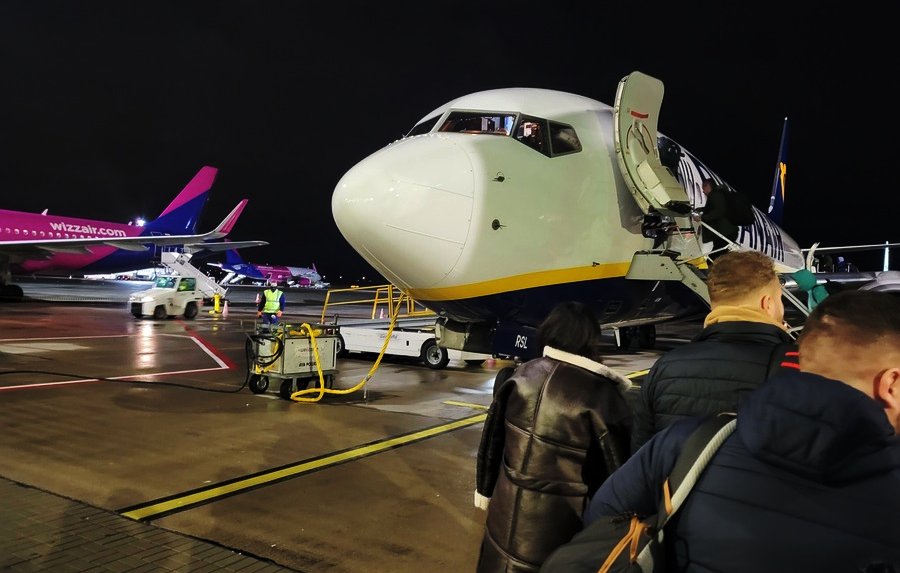 Pasażerowie wchodzący na pokład samolotu na lotnisku – możliwa podwyżka cen biletów lotniczych