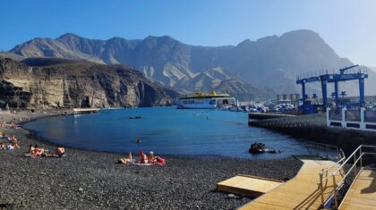 Plaża na Gran Canarii z turystami i łodziami na oceanie