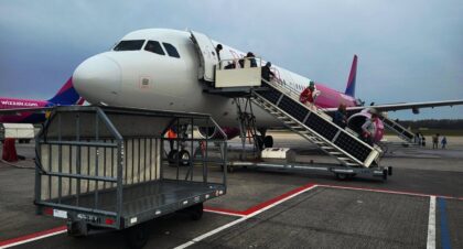 Pasażerowie schodzą po schodach z samolotu na płycie lotniska