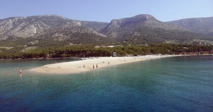 Plaża Zlatni Rat w Chorwacji z turystami i górami w tle