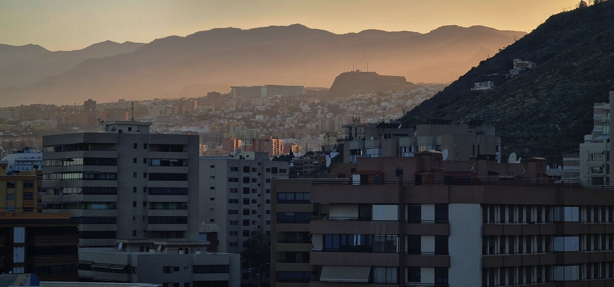 Czy Teneryfa jest bezpieczna? Panorama Santa Cruz de Tenerife o zachodzie słońca, z górami w tle i efektowną grą światła oraz cienia.