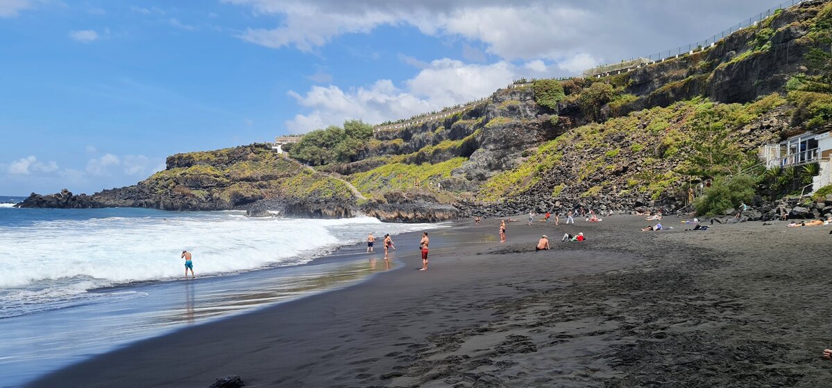 Czarny piasek i kąpiący się na Playa El Bollullo