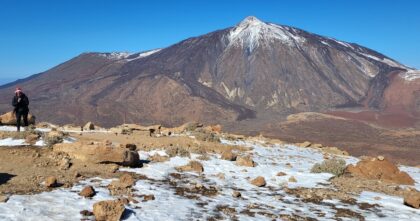 Rezerwacja na Teide – turystka idzie po śniegu, w tle ośnieżony wulkan Teide