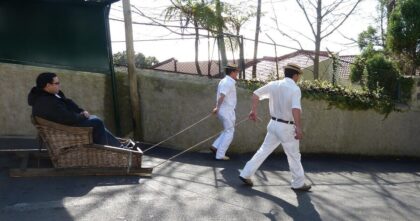 Wypadek toboganu na Maderze – turysta w wiklinowych saniach prowadzonych przez dwóch carreiros w Monte